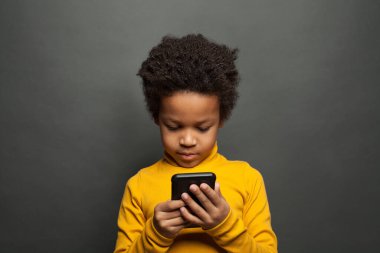 Akıllı telefon kullanan küçük siyah çocuk.