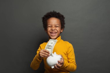 Para kutusu olan gülen siyah bir çocuk ve kara tahtada bir dolar.