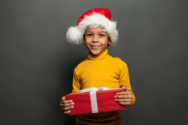 Criança Preta Bonito Chapéu Santa Segurando Presente Natal Vermelho Fundo — Fotografia de Stock