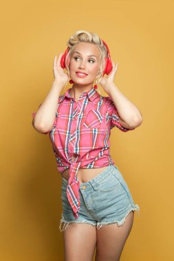 Kulaklıkla müzik dinleyen ve poz veren güzel bir kadın.