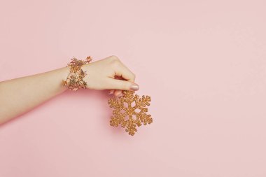 Pembe arka planda kadın eli olan Noel kar taneleri