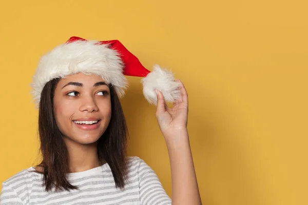 Sarı Arka Planda Noel Baba Şapkalı Siyah Kadın — Stok fotoğraf