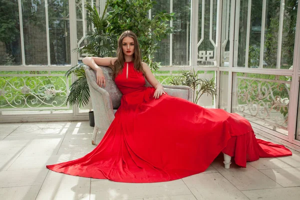Kırmızı Ipeksi Elbisesiyle Klasik Koltukta Oturan Zarif Ünlü Kadın — Stok fotoğraf