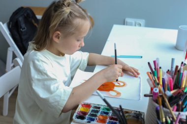 Evde resim yapan yaratıcı genç bir çocuk. İçerideki küçük kızın yakın plan portresi.