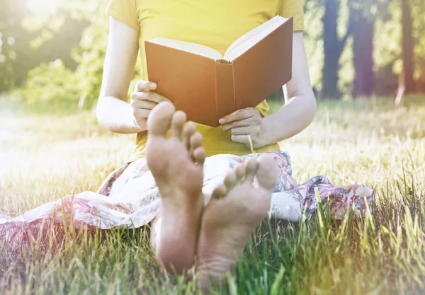 女孩读书书坐在温暖的夏天草 — 图库照片