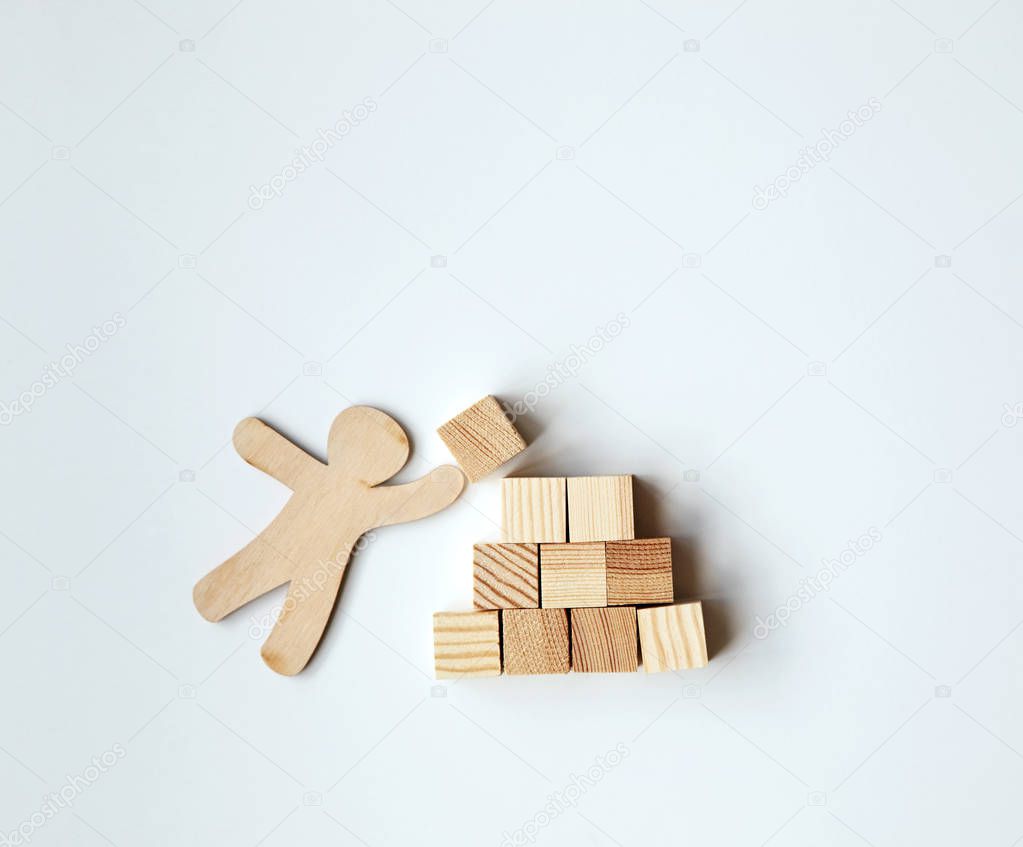 Little wooden man putting block on top of mountain as symbol. Achievement, success, leadership and construction concept