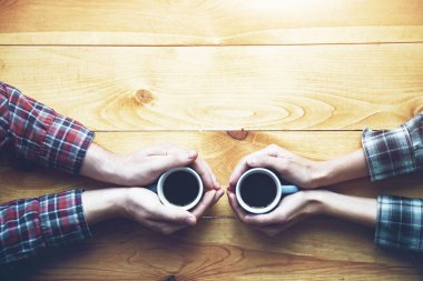 İki bardak kahve üzerinde ahşap masa, yükseltilmiş görünümü ile çift el