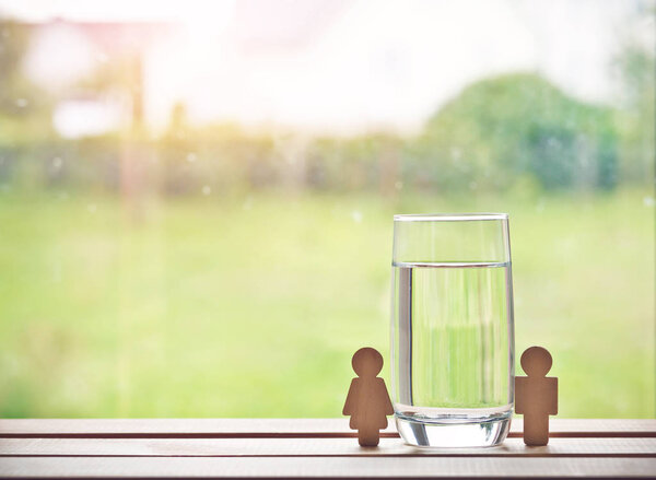 стакан воды с деревянной женщиной и мужчиной. Пространство для текста
