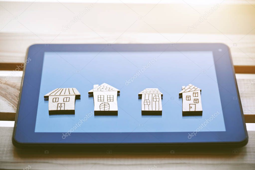 Wooden symbols of houses on digital tablet computer.  Online house choosing or rental of property concept