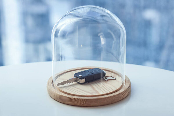 Car key under glass cap. Symbol of car insurance or automobile safet