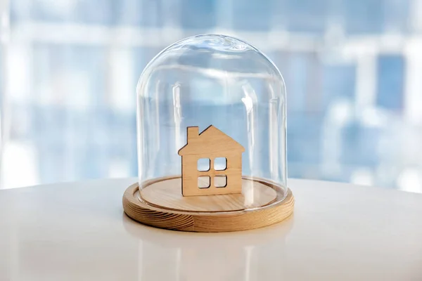 玻璃罩下的木制房屋模型 安全之家的象征保险或保护建筑物财产概念 免版税图库照片