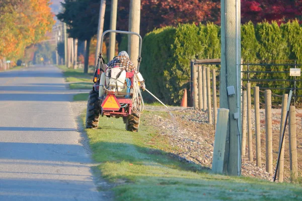 Farm Worker Drives His Small Utility Tractor While Using Hose — Stock Photo, Image