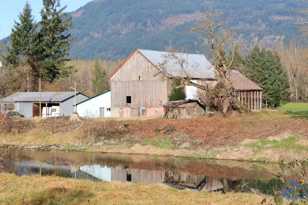 山谷中一条小溪旁的乡村古老的农场建筑的风景 — 图库照片