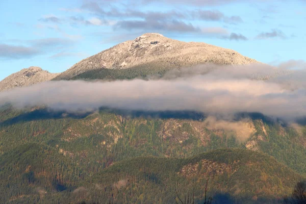 雲の薄いハローを囲む 初冬の季節の間に軽く雪に覆われた山 — ストック写真