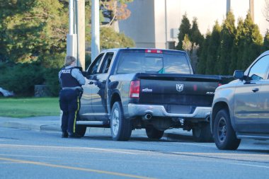 A female officer with the Royal Canadian Mounted Police (RCMP) deals with a driving infraction in Chilliwack, BC, Canada on December 30, 2018. clipart