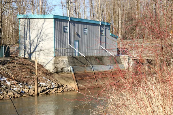 Medium view of a water pumping station set beside a creek where fresh water is drawn and distributed throughout the community.