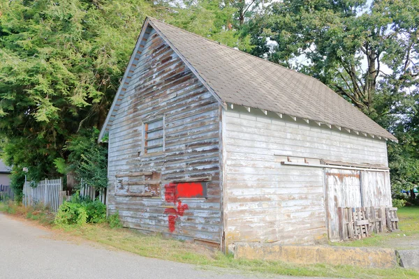 Three quarter profile view of an old back lane wood frame building that was used for many purposes over the years and is still in use today.