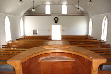 The Minister's pulpit in a small, conservative Christian church with wooden pews in the background.  clipart