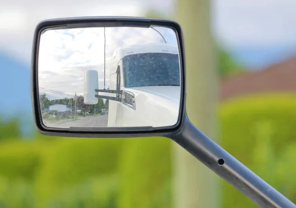 Close, detailed view of a modern semi trailer truck and the reflection in its rear view mirror.