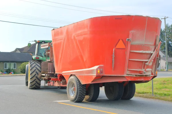 Close reverse view of a tractor hauling equipment used for transporting livestock feed mix.