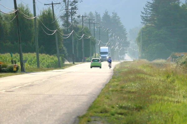 大規模なトラックが対向車線に近づくと 農村部の道路上のサイクリストを通過した小さな車がレース危険な事件 — ストック写真