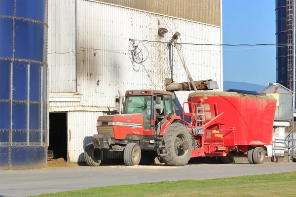 拖拉机停在一个筒仓旁边 在那里谷物填满了连接拖拉机的推车 — 图库照片