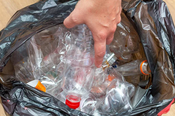 Black packet with lot of used plastic bottles for recycling in hands