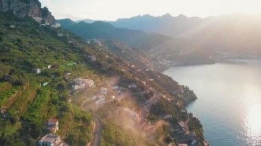 Amalfi cliffside köyü büyüleyici bir manzarası ile parlayan Güneşin dağların arkasında bir bakış.