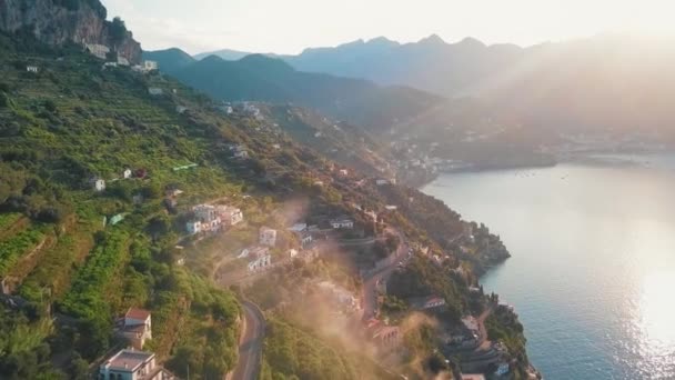 の後ろに太陽の光を垣間見ることとアマルフィ クリフサイド村の魅惑的な眺め — ストック動画