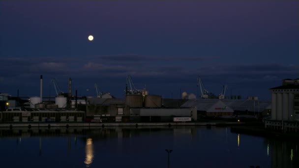 背の高いクレーンと貨物家に沿って取引港の夜空に満月の上昇します — ストック動画