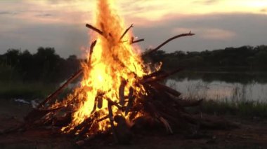Bir şenlik ateşi Batışı manzarasına sahip göl yanında.