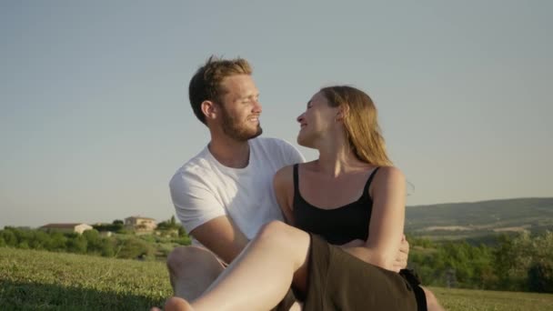 Jong Echt Paar Zittend Een Veld Praten Tijdens Het Zoenen — Stockvideo