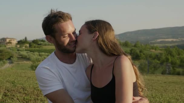 キスしてハグ フィールドに座って若いカップルのロマンチックな景色 — ストック動画