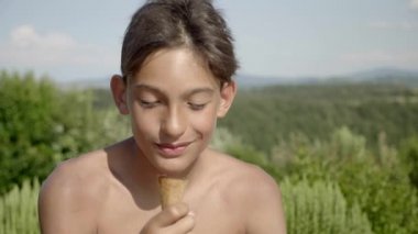 Alan arka plan üzerinde bir görünümü ile bir yaz gününde dondurma yeme mutlu bir genç çocuk.