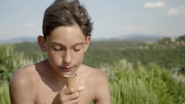 背景にフィールドと青い空の景色をリラックスしながらアイスクリームを食べる子供 — ストック動画
