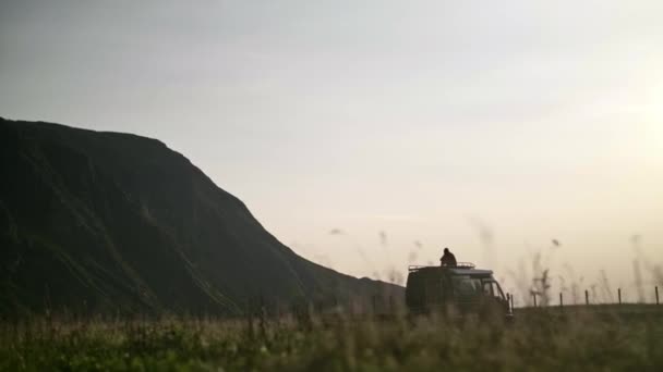 Silhueta Homem Sentado Topo Uma Van Campista Olhando Para Montanha — Vídeo de Stock
