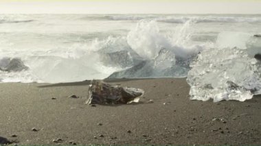 Diamond Beach büyük adet buz blokları ile aracılığıyla çökmesini dalgalar bir closeup video.