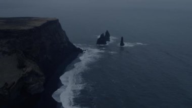 Panoramik İzlanda'nın Reynisfjara cliff, sütunlar ve siyah kum plaj dalgalar kıyıya çökmesine devam.