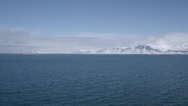 アイスランドの雪に覆われた山脈と海の広角ショット 明確な空 — ストック動画