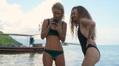 Kız arkadaşlar iPhone'da fotoğraflara bakarken Koh Tean plajda sığ Dof atış.