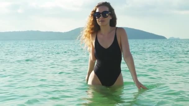 眼鏡と黒いワンピース ビキニ ビーチから海岸に向かって歩いてモデルの安定したショット — ストック動画