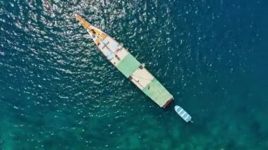 Mavi renkli kristal berraklığında suları üzerinde yüzen Bali tekne