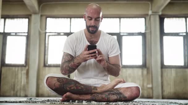 Instruktor jogi za pomocą telefonu następnie wraca do medytacji — Wideo stockowe