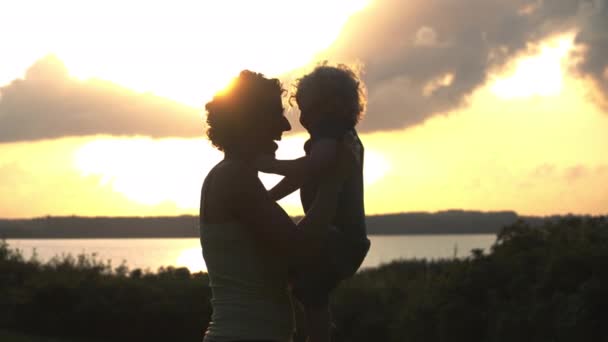 Una vista de la tarde de las siluetas de madre e hijo divirtiéndose juntos — Vídeo de stock