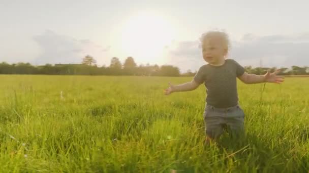 Un tout-petit joufflu joyeux marchant dans l'herbe haute dans Slowmotion — Video