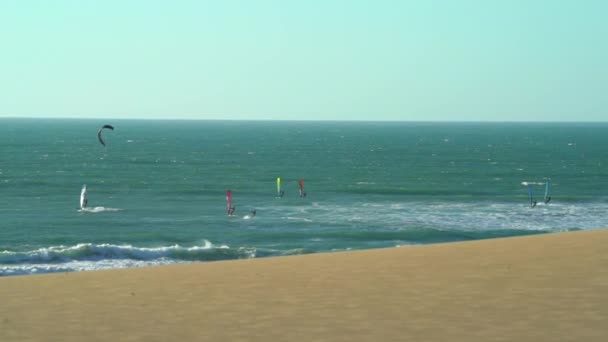 Breed shot van mensen kitesurfen, Zeilboten en Golven Crashen op het strand — Stockvideo