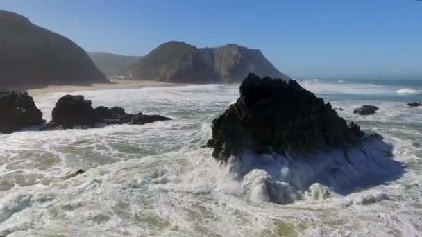 Orbitando plano de una playa rocosa revelando paisajes de montañas — Vídeo de stock