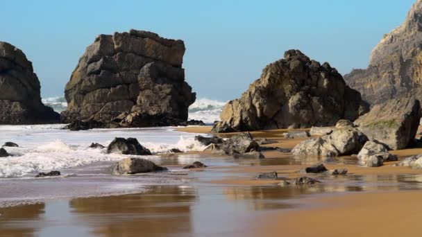Steady Shot of Waves на пляже с валунами на закате — стоковое видео