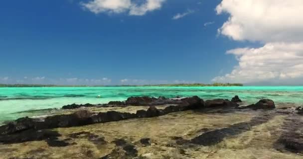 열 대의 섬에 있는 바위투성이의 얕은 물 위를 나는 비행기 — 비디오