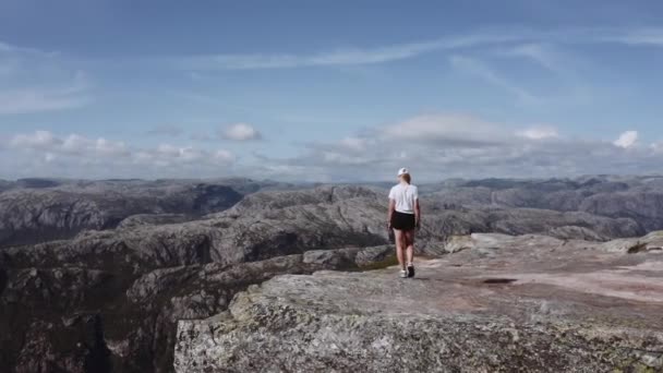 Luchtfoto van een vrouw die langs de rand van een klif loopt tijdens een ochtendwandeling — Stockvideo